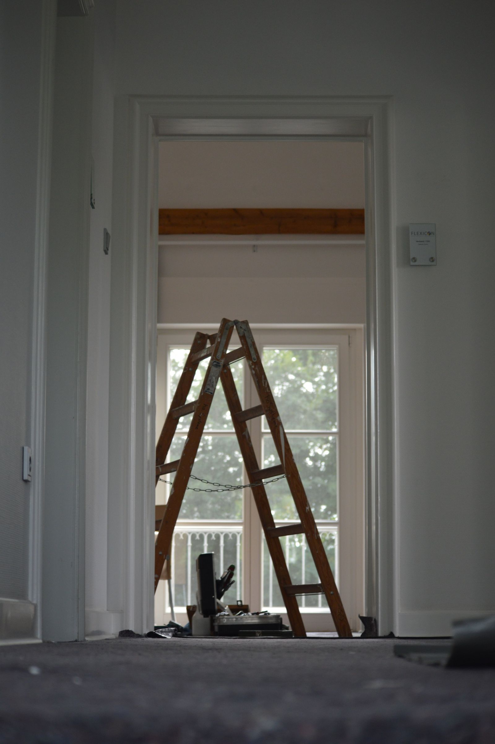 Interior room prepared for finishing work, with a ladder set up by the doorway