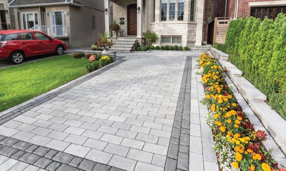 Paver driveway and walkway with planted edging beside a home