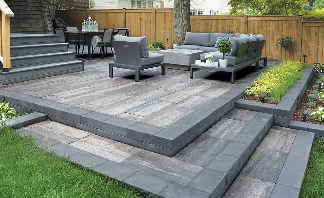 Raised paver patio with seating steps and planted borders
